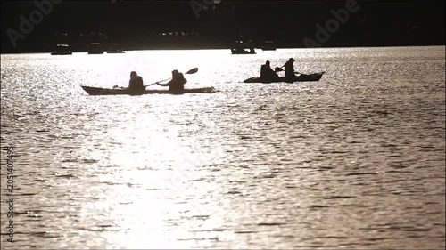 Silhouettes of people rowing boats can be seen at the public pond.