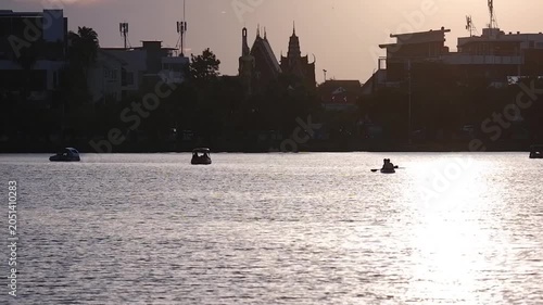 Silhouettes of people rowing boats can be seen at the public pond.