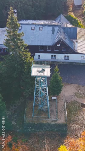 Explore the Slovanka lookout tower in the Jizera Mountains surrounded by vibrant autumn colors. Experience breathtaking aerial views of this historic metal structure and the lush forest.