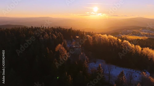 Stepanka Lookout Tower is located in the Jizera Mountains. The sun sets over the trees, creating a warm glow in winter and autumn. Explore this natural beauty during your hike.