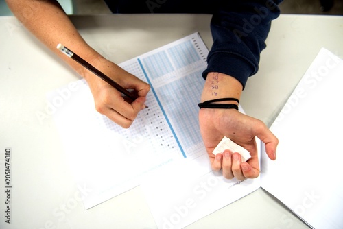 Foto Person taking a test, writing answers on a paper with a pencil.