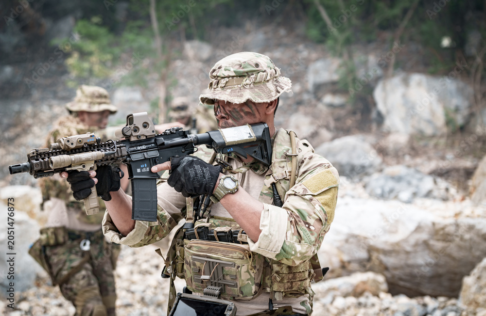 Fototapeta premium Special forces soldier in camouflage aiming a rifle during a tactical operation