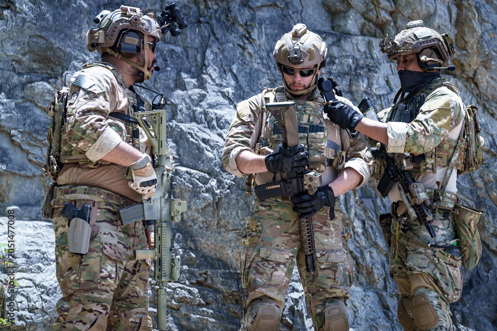 Fototapeta premium Special forces soldiers in tactical gear with rifles in a rocky, arid environment