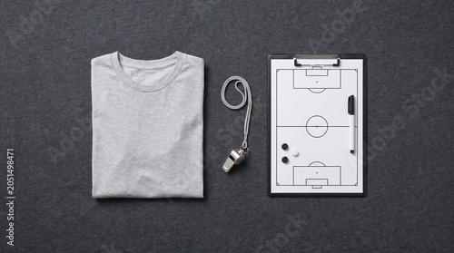 Soccer T-shirt with tactical board and referee whistle on grey background