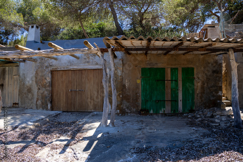 «Ibiza, Spain»; May 26 2026: Sa Caleta traditional fisherman huts and rustic wooden docks in a narrow rocky bay, showcasing the historic coastal heritage and turquoise Mediterranean sea.