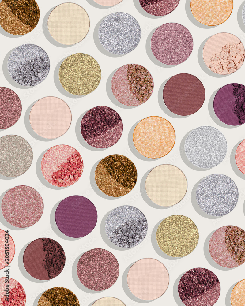 Fototapeta premium Pattern of colorful eyeshadow pans with matte, shimmer, metallic, crushed powder textures. Minimal cosmetics background, colored swatches of compact powder for makeup. Contemporary cosmetic aesthetic