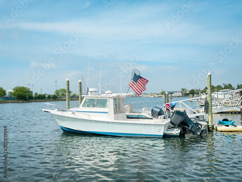 Motorboat with American flag docked at marina on a calm sunny summer day