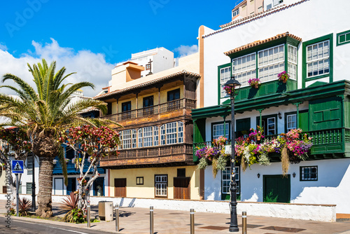 Intricately detailed traditional dark green wooden balconies are bursting with vibrant multi-coloured flowers in Santa Cruz town, La Palma, Canary Islands, Spain