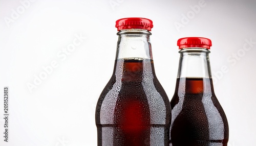 refreshing cold glass bottle of brown soda drink red cap cola dark fizzy on white background