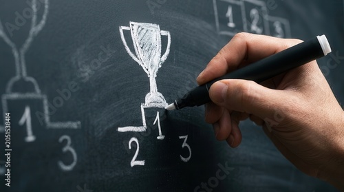 Creative concept of achievement and competition results shown as a hand drawing a trophy and ranking numbers on a chalkboard.