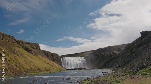 Family on vacation visiting scenic waterfall in Iceland sunny summer day