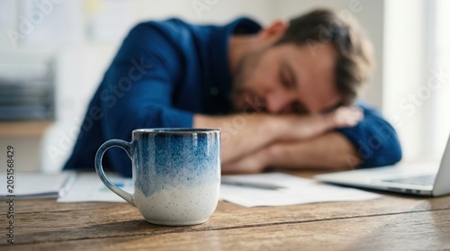 Fatigue risk management concept showing a person exhausted and resting near a coffee cup.