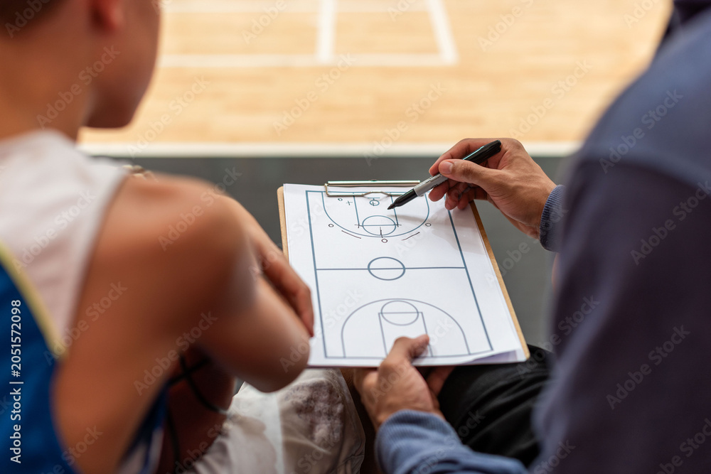 Naklejka premium Coach discusses basketball strategy with player using a clipboard.