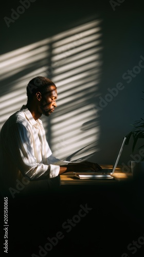 Focused Black Man Working on Laptop in Natural Light
