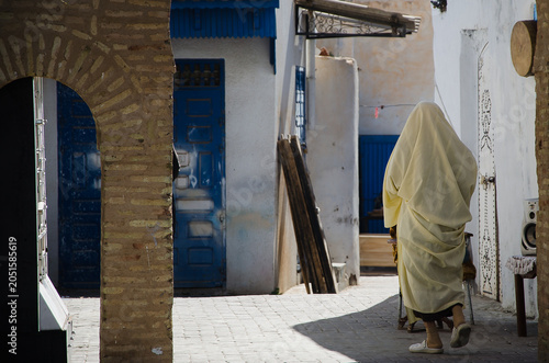 Photos Back view of a woman wearing traditional sefsari walking in a narrow alleyway in