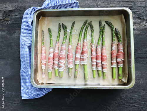 Prosciutto wrapped asparagus spears on a baking sheet