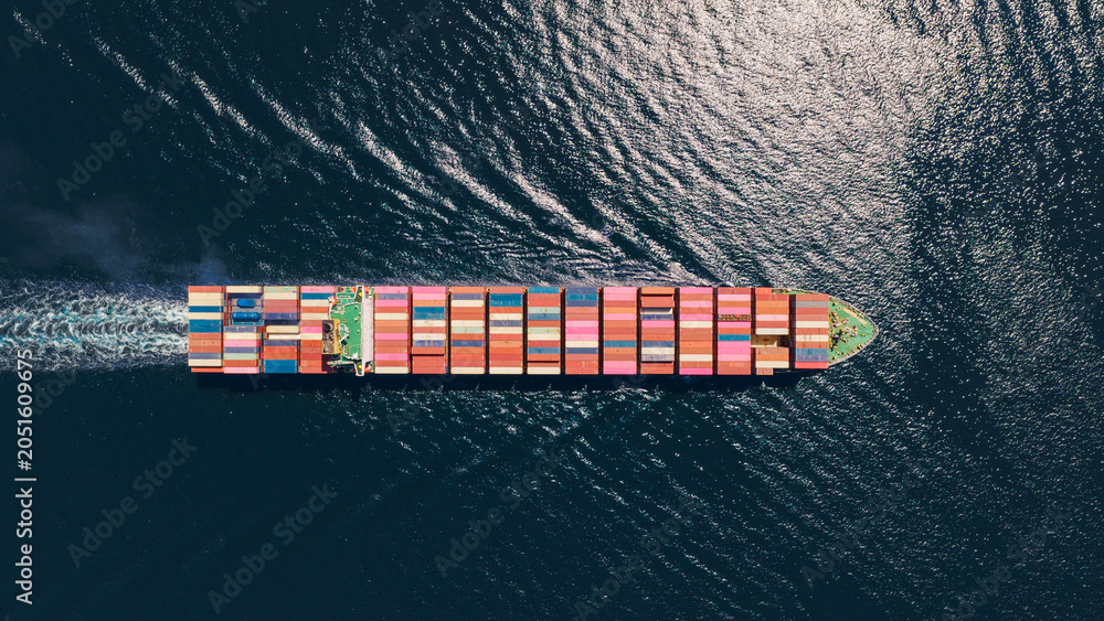 Fototapeta premium Container vessel carrying numerous shipping containers across the open sea, symbolizing global trade, international logistics, and maritime transportation, seen from a high aerial perspective