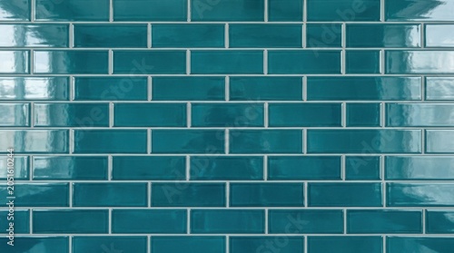 Teal glossy subway tile wall texture with a blue green brick pattern and ceramic grout lines. Modern interior surface for a