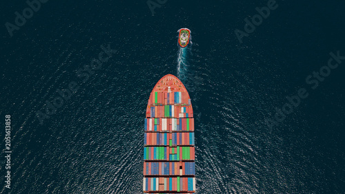 Obraz na plátně Container ship navigating through deep blue ocean with a tugboat trailing behind