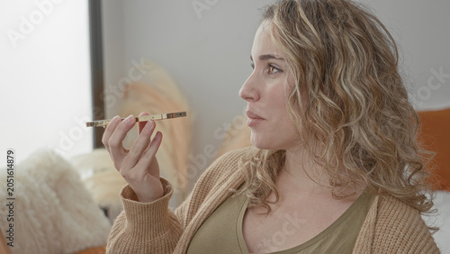 Foto Woman holding smartphone to mouth speaking into speakerphone in studio, wearing knit sweater and seated on sofa near window; serene conversation connection
