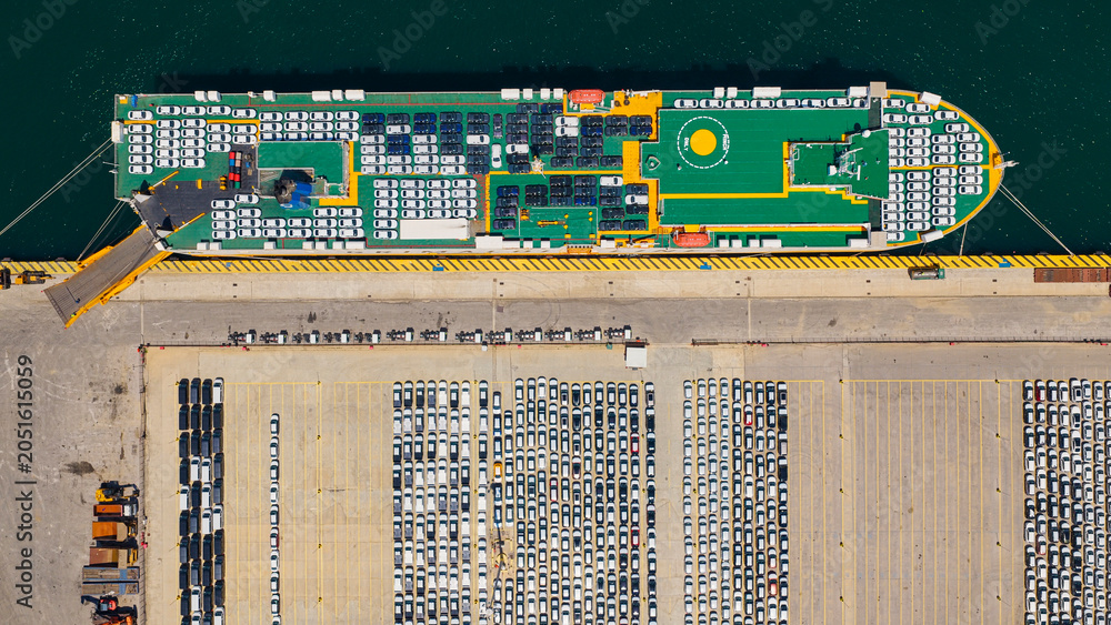 Fototapeta premium Car carrier ship docked at an industrial port, actively loading and unloading new vehicles for global distribution across the modern automotive logistics infrastructure