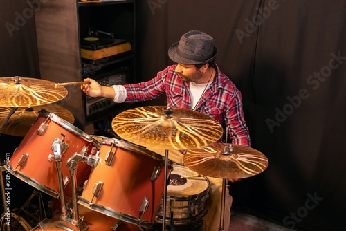 Canvas Print Concentrated man playing percussion instrument in a dark music studio, rock or j