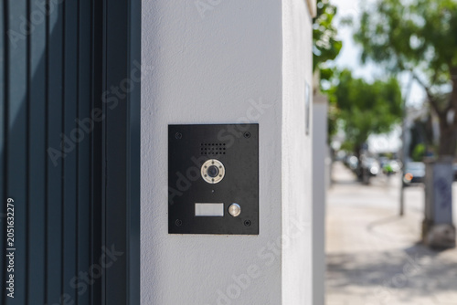 Modern video intercom system installed on residential building entrance wall, smart home access control technology with doorbell camera