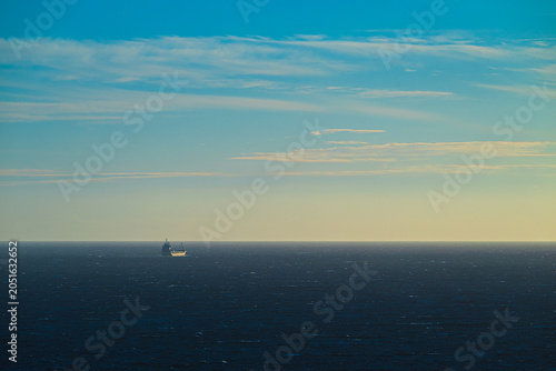 Foto lone cargo vessel crossing dark ocean beneath expansive pastel sky