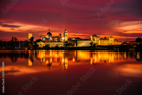 Scenic sunset view of Mantua skyline in Lombardy, Italy; twilight golden hour view of the medieval town reflected in the lake waters