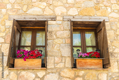 Valokuva Stone house windows with colorful flower boxes on traditional medieval facade in