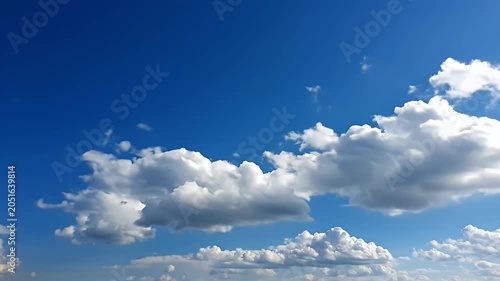 Scattered white clouds drifting across a clear blue sky.