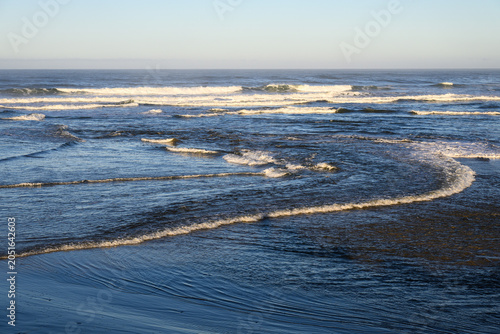 Wave curves into ocean waves breaking on approach to beach with clear horizon