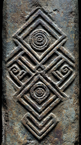 Weathered grey monolith with concentric eyes and chevron patterns