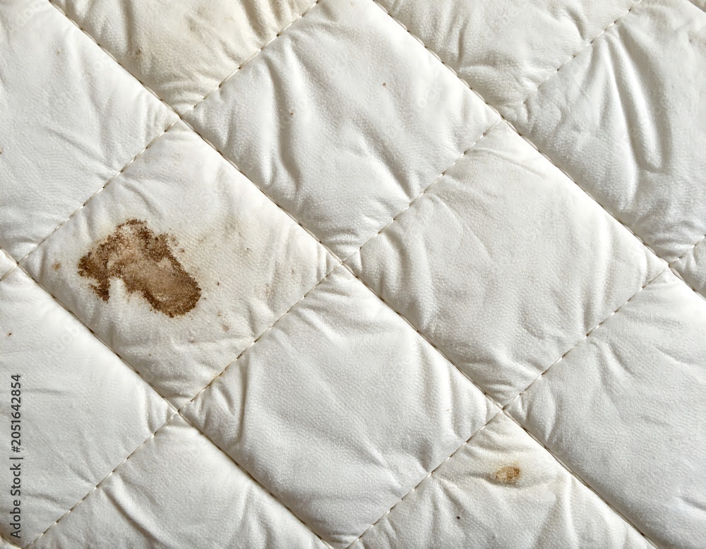 Naklejka premium Close-up of a white, quilted surface with dark brown stains, showcasing texture and imperfections in the fabric
