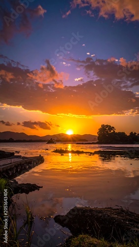 A serene sunset over a tranquil body of water with a walkway