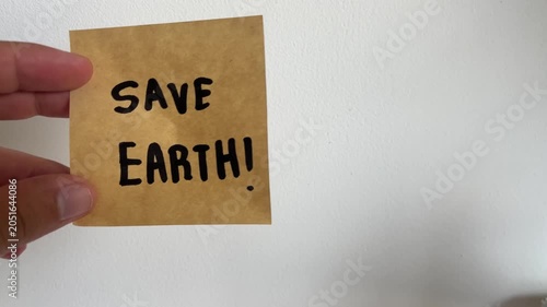 Hand holding kraft paper sign with handwritten Save Earth message on white background