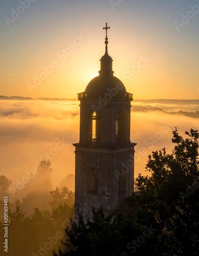 A serene tower stands amidst foggy landscape at sunrise