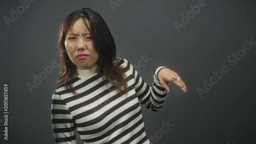 Tableau sur toile Woman with striped sweater raises hand and pushes away in studio in a dismissive gesture; disgust rejection