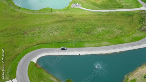 cinematic aerial view of car driving next to pond