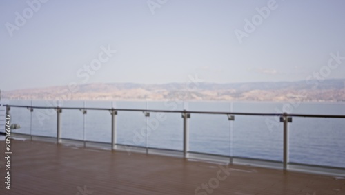 Obraz na płótnie Boat deck with glass railing and distant shoreline softly defocused with shallow bokeh, outdoor; background backdrop copyspace calm