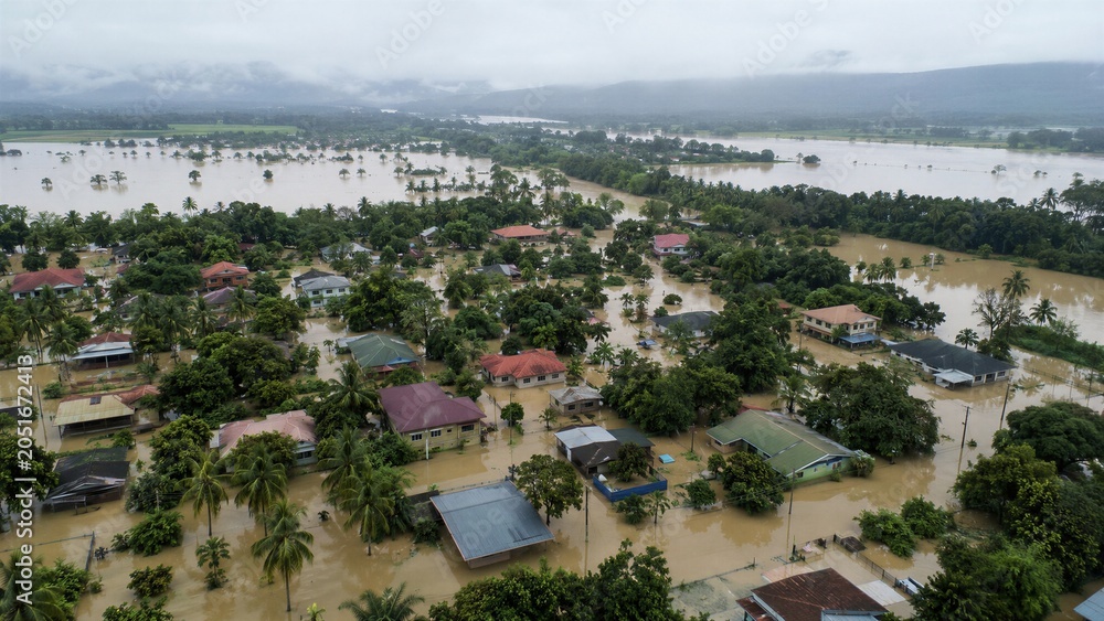 Obraz premium Severe flooding covers a rural tropical community with murky water, showing the devastating impact of extreme weather and climate change.