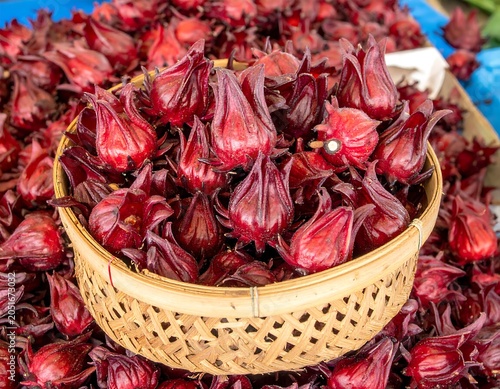 Close-up of a woven basket overflowing with vibrant red, bud-like blossoms, surrounded by a multitude of similar specimens