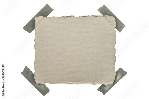 A square piece of textured off-white paper with rough deckled edges attached to a black background, with four strips, of adhesive tape