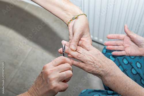 Nail trimming procedure for an elderly person performed by hand. personal care, hygiene, home support.