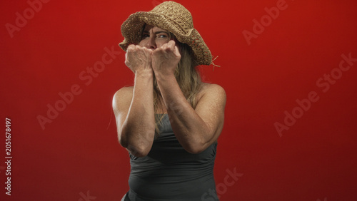 Foto Woman with raised fists and bare arms holding a defensive boxing pose in studio against a red seamless backdrop; self defense defiance