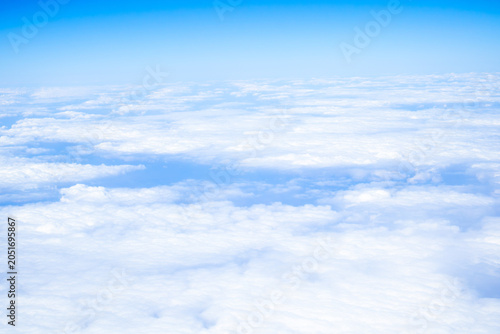 Aerial view of a vast layer of white clouds seen from an airplane flying above Europe. Peaceful sky landscape with soft cloud formations and blue atmosphere