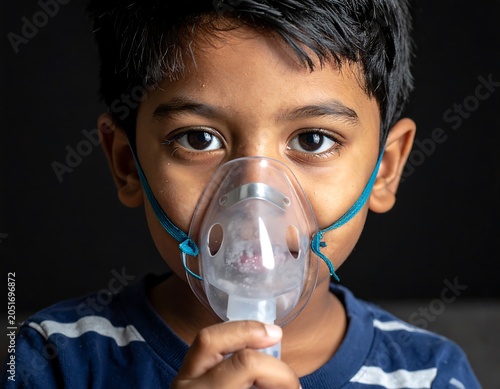 Close-up of a young child with an oxygen mask. Dark background and focused gaze. Child's skin is dark