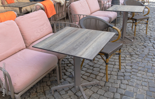 Comfortable outdoor cafe seating area featuring cushioned sofas, chairs and tables on a cobblestone street in Bucharest, Romania