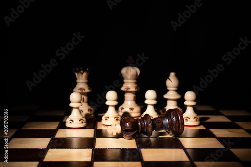 Bild auf Leinwand Chess king lying defeated among standing pieces on a board, symbolizing strategy, leadership, victory, failure, decision‑making, competition and business conflict