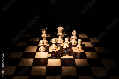 Photos Chess king lying defeated among standing pieces on a board, symbolizing strategy, leadership, victory, failure, decision‑making, competition and business conflict